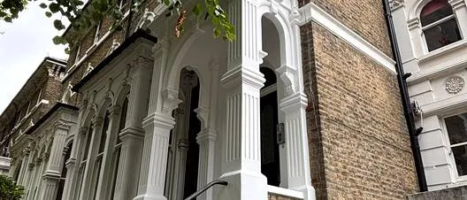 Angled view along a Victorian villa facade with its restored portico and bay window, Highbury N5
